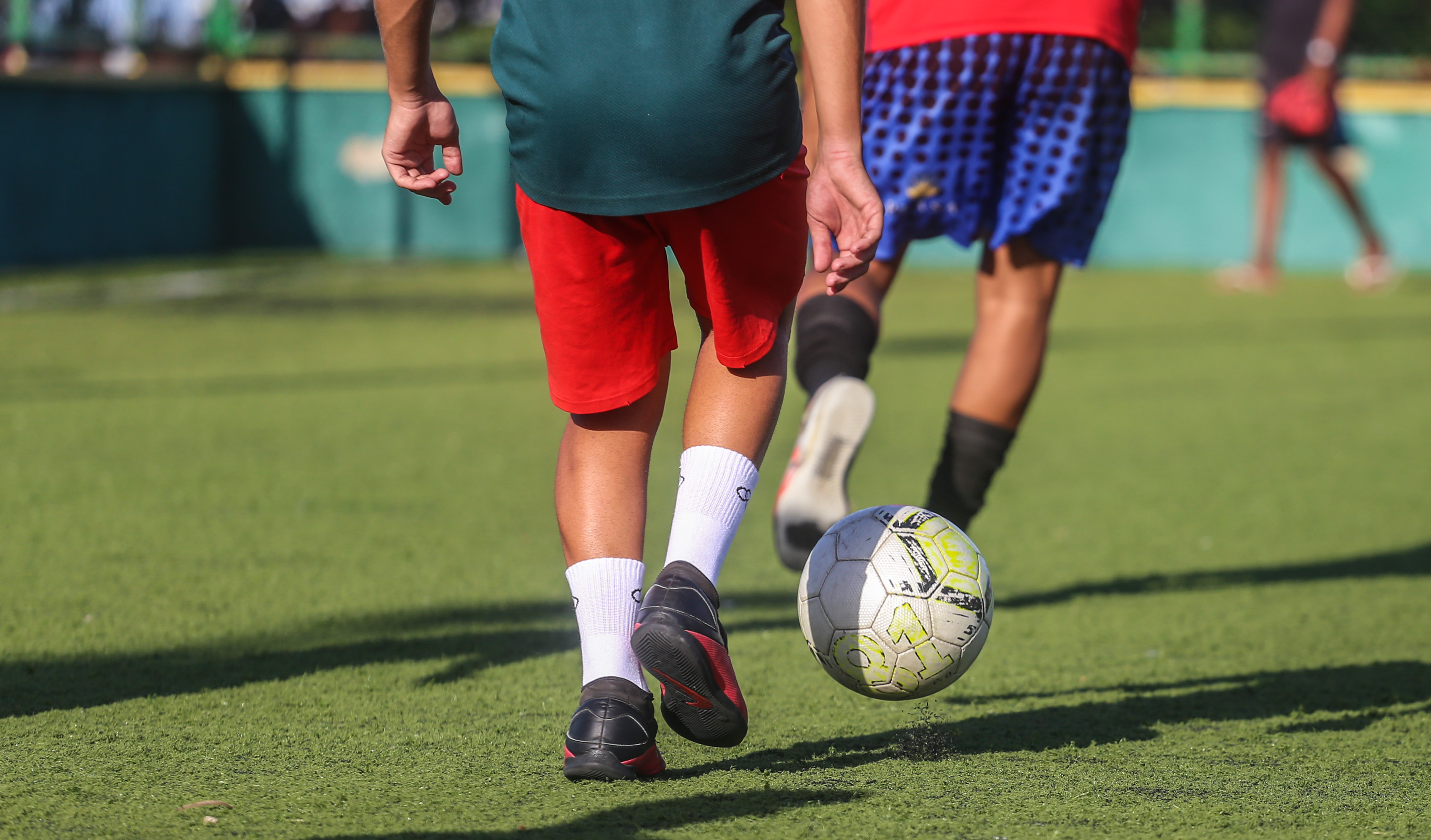 a foto mostra as pernas de dois garotos jogando bola